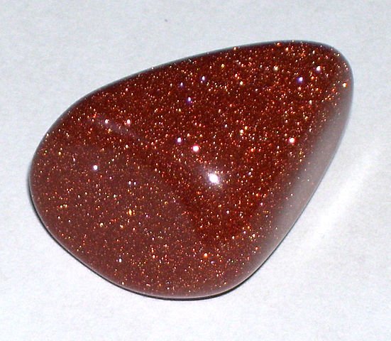 This stone absorbs most photons but reflects ones in the red wavelength, so it appears red.